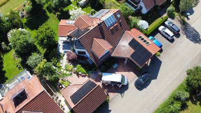 Luftaufnahme eines Wohnhauses, dessen Photovoltaikanlage sich über zwei Dachflächen zieht