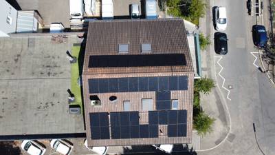 Luftaufnahme eines Mehrfamilienhauses mit Photovoltaikanlage auf dem Satteldach