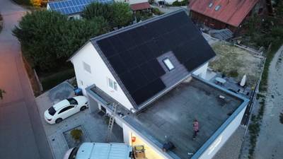 Luftaufnahme eines Wohnhauses mit vollflächiger Photovoltaikanlage auf dem dunklen Satteldach