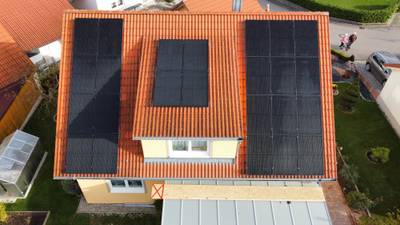 Luftaufnahme eines Wohnhauses mit Photovoltaikmodulen auf beiden Dachseiten