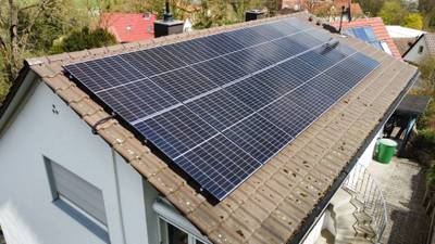 Luftaufnahme einer Photovoltaikanlage auf einem Wohnhausdach im Gegenlicht