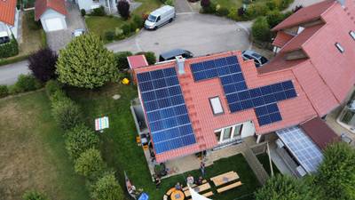 Luftaufnahme eines Wohnhauses mit Photovoltaikanlage auf dem roten Ziegeldach